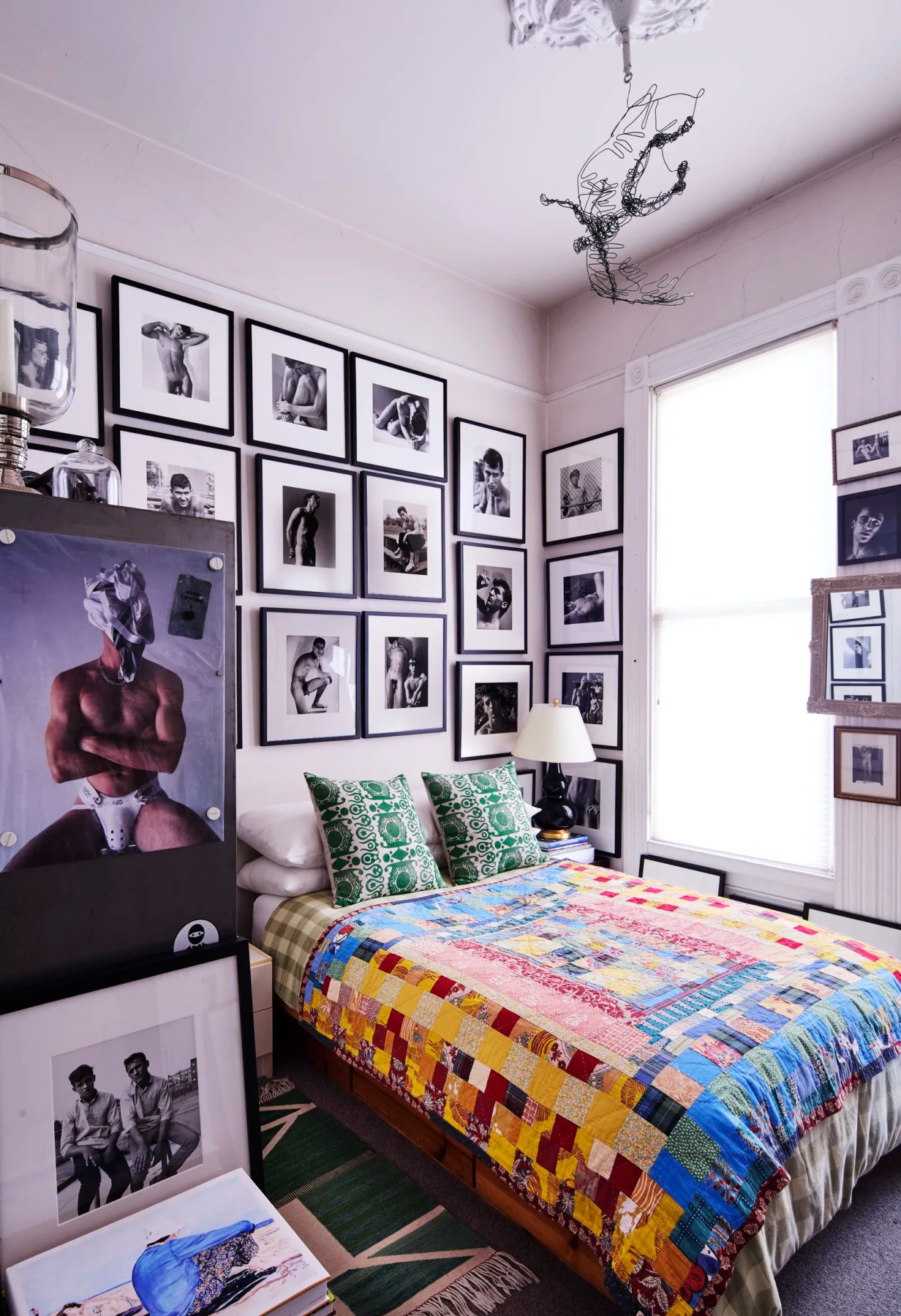 A bedroom with a salon-style display of mostly black-and-white male nude photographs and portraits, primarily by photographer Danny Fitzgerald of Les Demi Dieux.